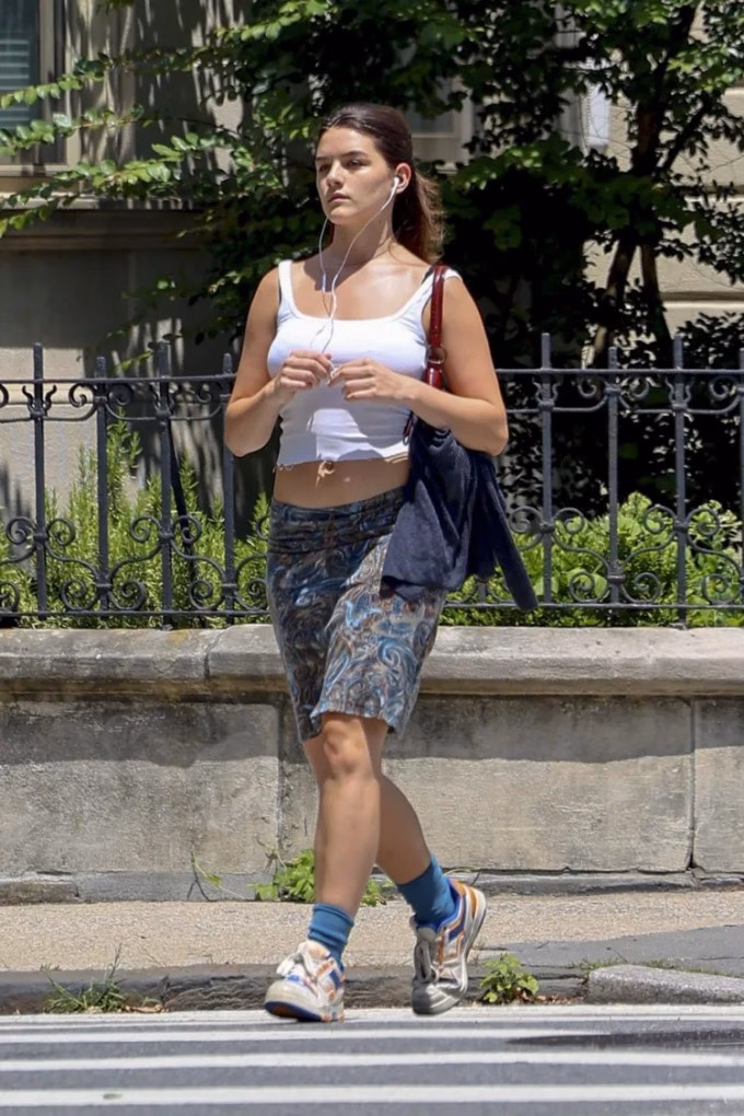 Một ngày trước đó, Suri chống chọi cái nắng nóng mùa hè với áo crop top và váy ngắn. Tờ Instyle bình luận 'con gái 19 tuổi của Tom Cruise dạo phố New York với phong cách đúng chuẩn Gen Z'. Suri kết hợp trang phục trẻ trung với chiếc túi quai ngắn màu nâu đỏ, giày thể thao Pony và tai nghe có dây của Apple.
