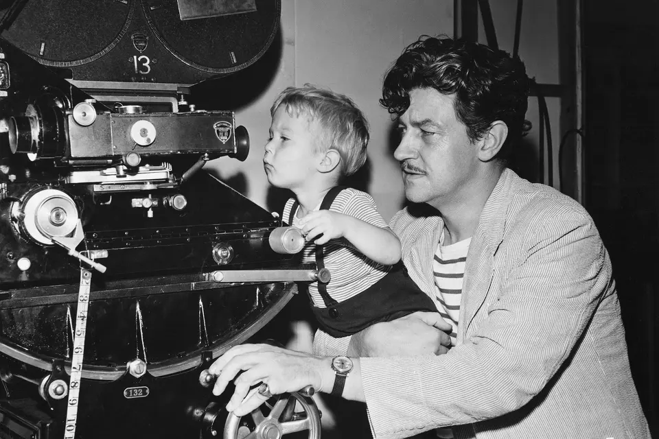 Preston Sturges helps a child look through a camera, 1940.