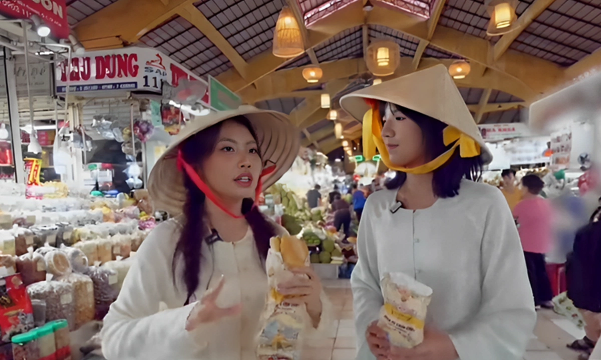 Tại chợ Bến Thành, Phương Mỹ Chi chiêu đãi Khả Lâu bánh mỳ, gỏi cuốn và nhiều món ăn vặt khác. Khả Lâu hưởng ứng nhiệt tình, ăn ngon miệng.