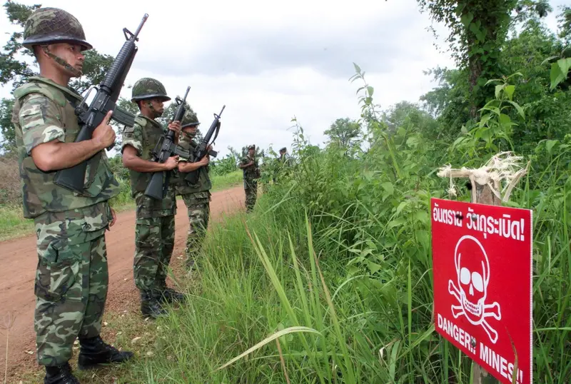 Chụp lại hình ảnh, Ảnh minh họa: Binh lính Thái Lan tuần tra dọc theo một con đường biên giới với Campuchia, đi ngang qua một biển cảnh báo về mìn