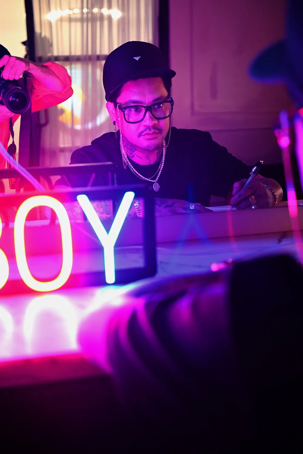 A tattoo artist working in a studio, neon sign in the foreground