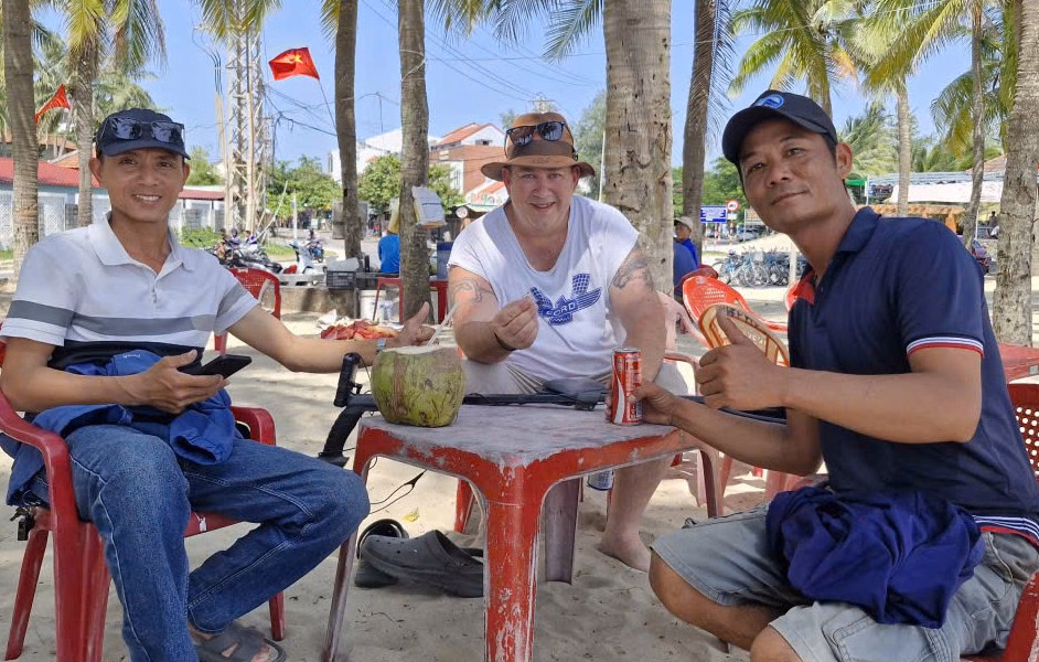 Nam du khách cầm trên tay chiếc nhẫn sau khi được anh Trinh (bìa phải) và anh Đông hỗ trợ tìm thấy. Ảnh: G.X