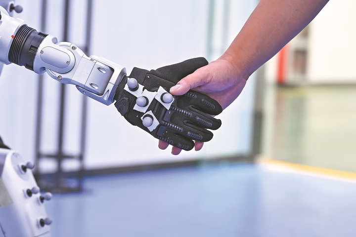 Gen Z tiếp cận tài chính thông minh với công nghệ AI và động lực xuất khẩu trực tuyến Một robot hình người bắt tay với một nhân viên tại một công ty thiết bị thông minh. (Nguồn: Xinhua)