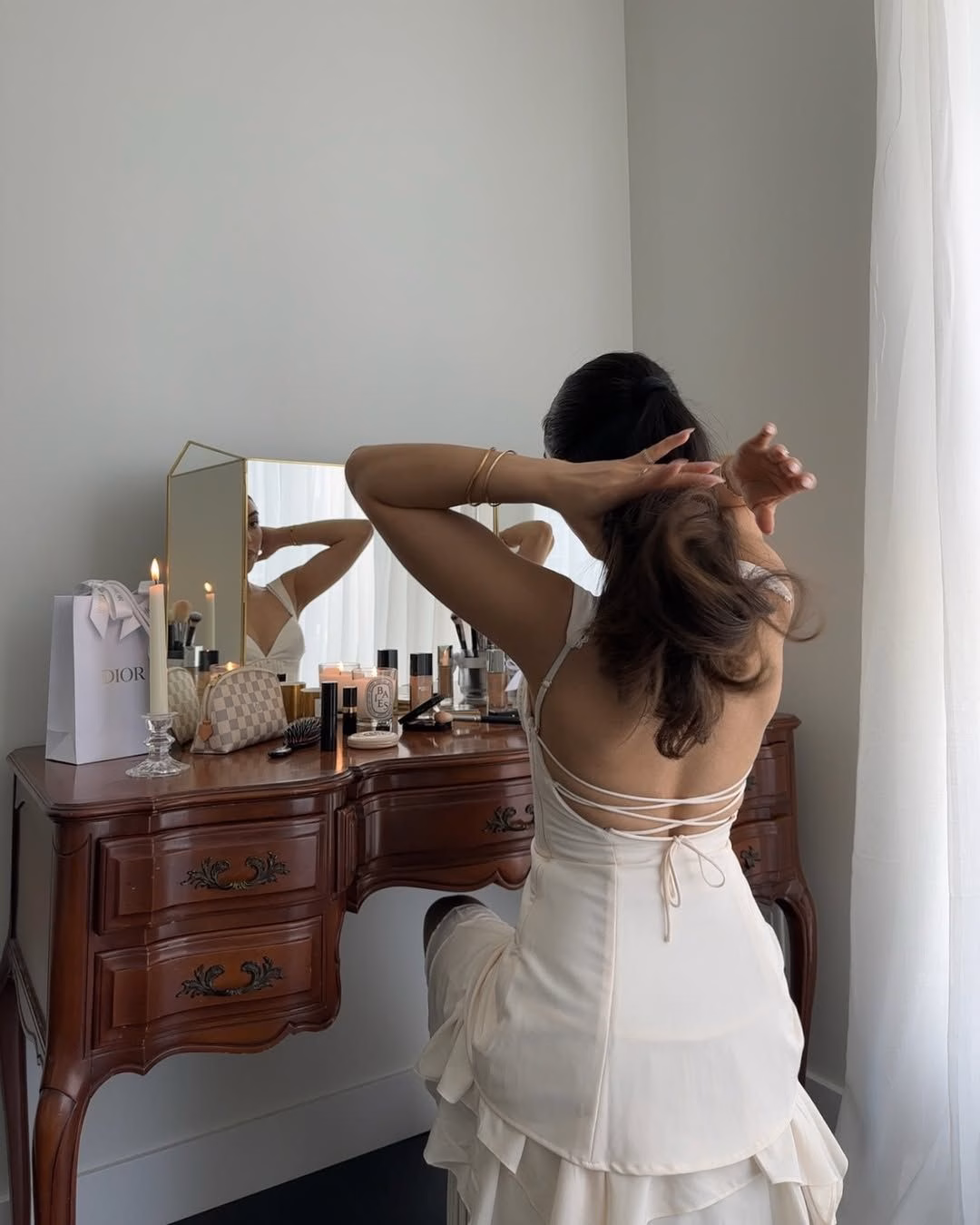 15 món beauty giúp tôi nâng tầm routine skincare và décor nhà Mobina Peiman sits at her vintage vanity while doing her hair.