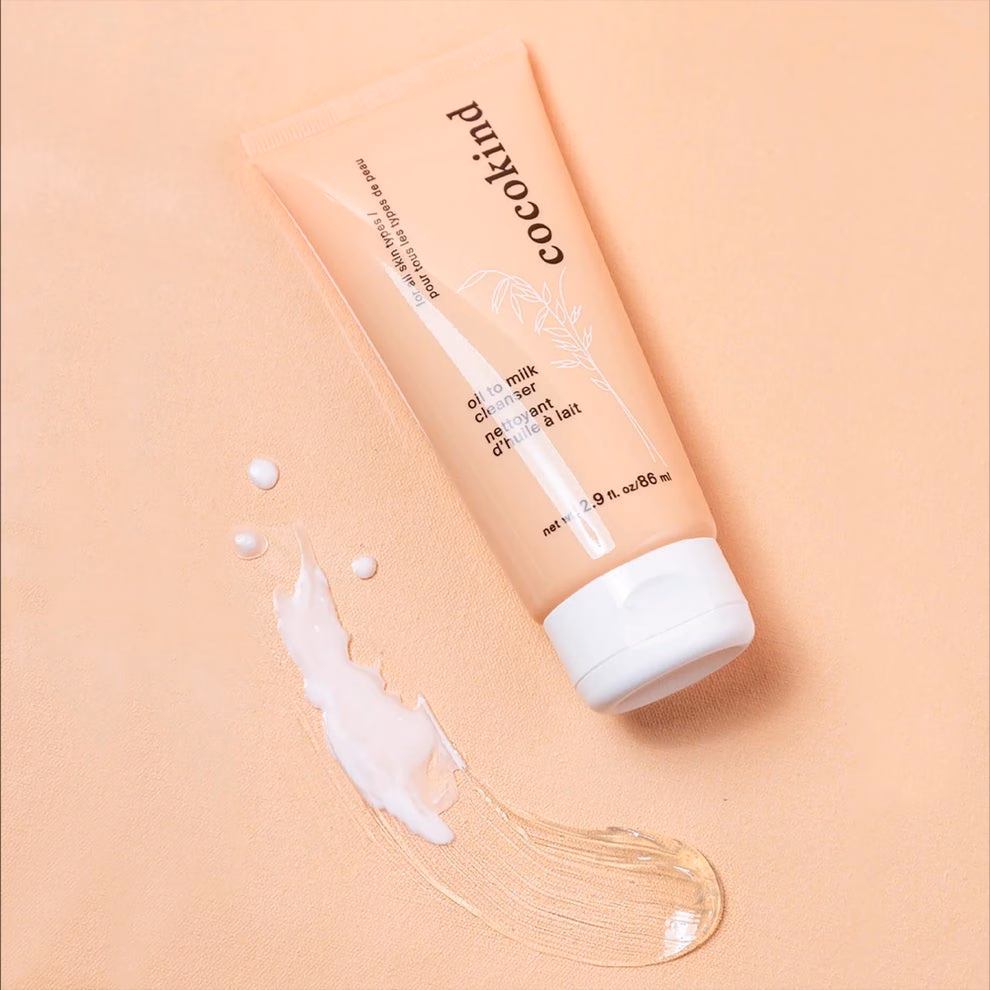 Cocokind oil to milk cleanser tube on a smooth surface with a dab of cleanser beside it, featured in a shopping article