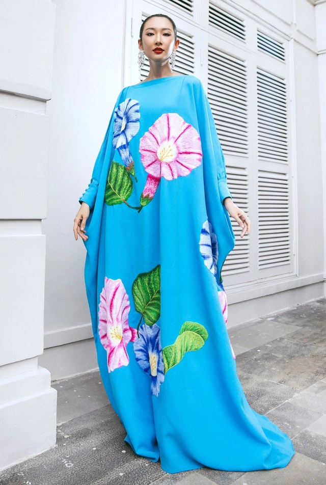 Phom đầm freesize cổ điển luôn được yêu thích vì khéo léo giấu nhược điểm hình thể, phù hợp với mọi độ tuổi và mọi vóc dáng. Thiết kế tông xanh họa tiết thêu hoa muống biển nổi bật được người đẹp Thanh Khoa phối cùng bông tai thả dài điệu đà