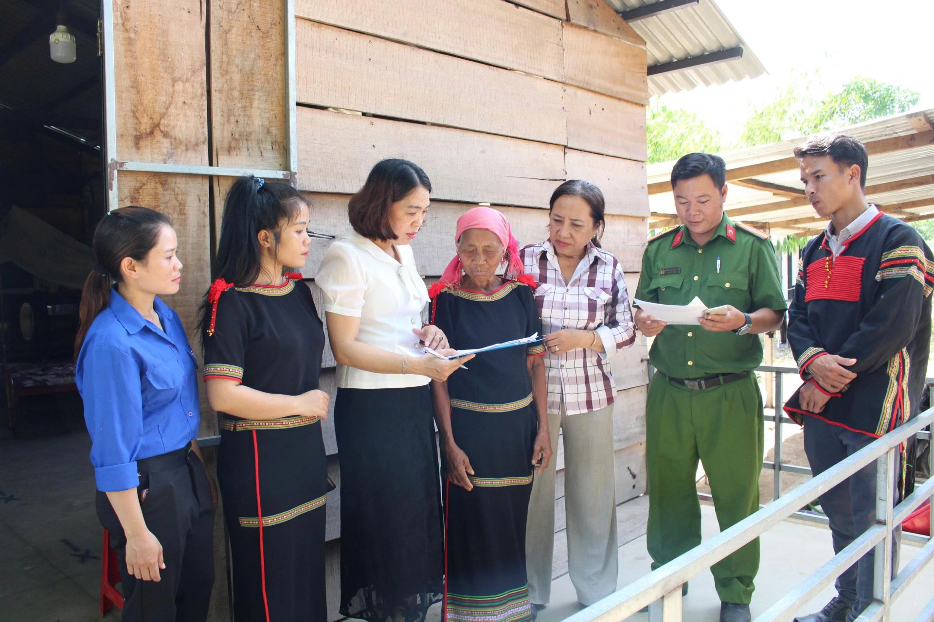 Cán bộ Trung tâm Phục vụ hành chính công xã Trung Khánh Vĩnh cùng công an, đoàn viên, trưởng thôn Hòn Lay hướng dẫn bà Niê H’Dua thực hiện thủ tục hành chính tại nhà.