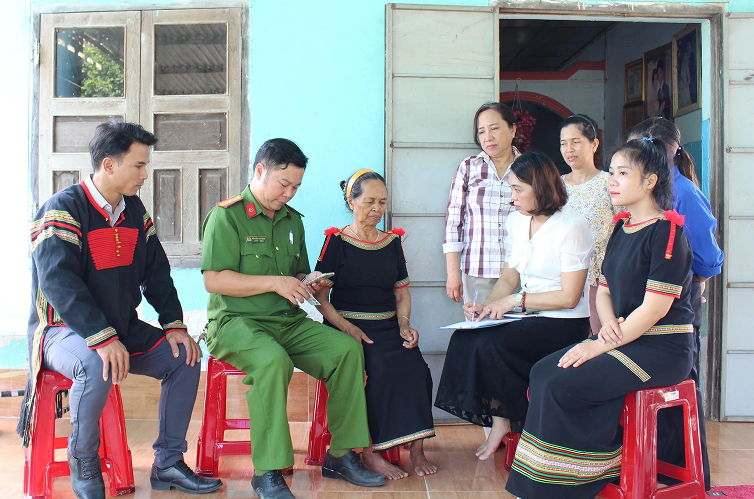 Cán bộ Trung tâm Phục vụ hành chính công xã Trung Khánh Vĩnh cùng công an, đoàn viên, trưởng thôn Hòn Lay hướng dẫn bà H'Đi thực hiện thủ tục hành chính tại nhà.