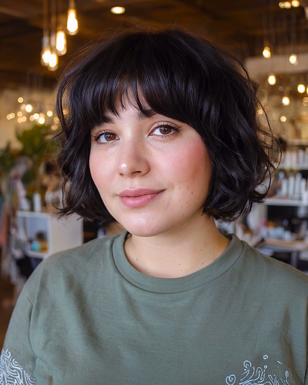 Chin-length curly black bob with bangs flattering for round face shapes