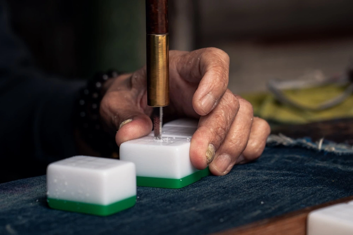 Bà dùng một công cụ giống chiếc vặn nút chai được dùng để khoan các họa tiết lên mặt quân cờ.