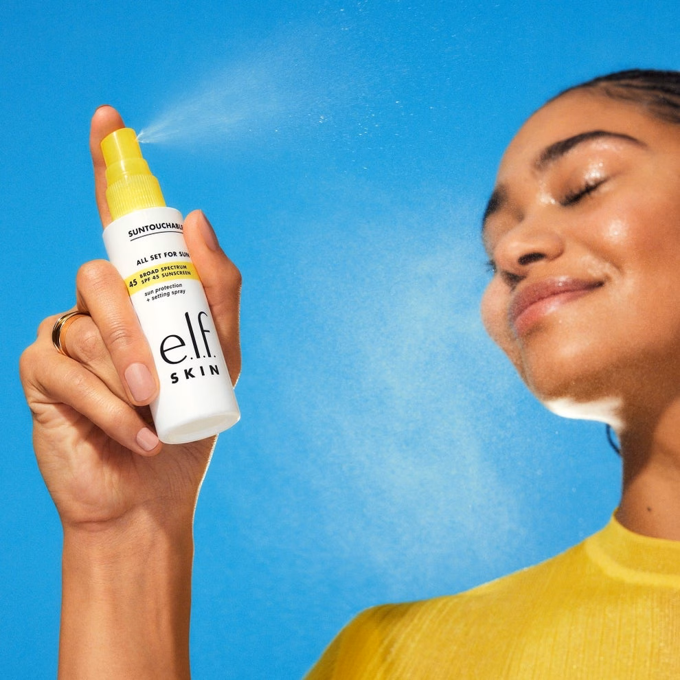 3 sản phẩm chăm sóc da và môi giúp giảm đỏ, mịn màng và cấp ẩm Person spraying e.l.f. SKIN setting spray on face, smiling with eyes closed, in a shopping-themed image