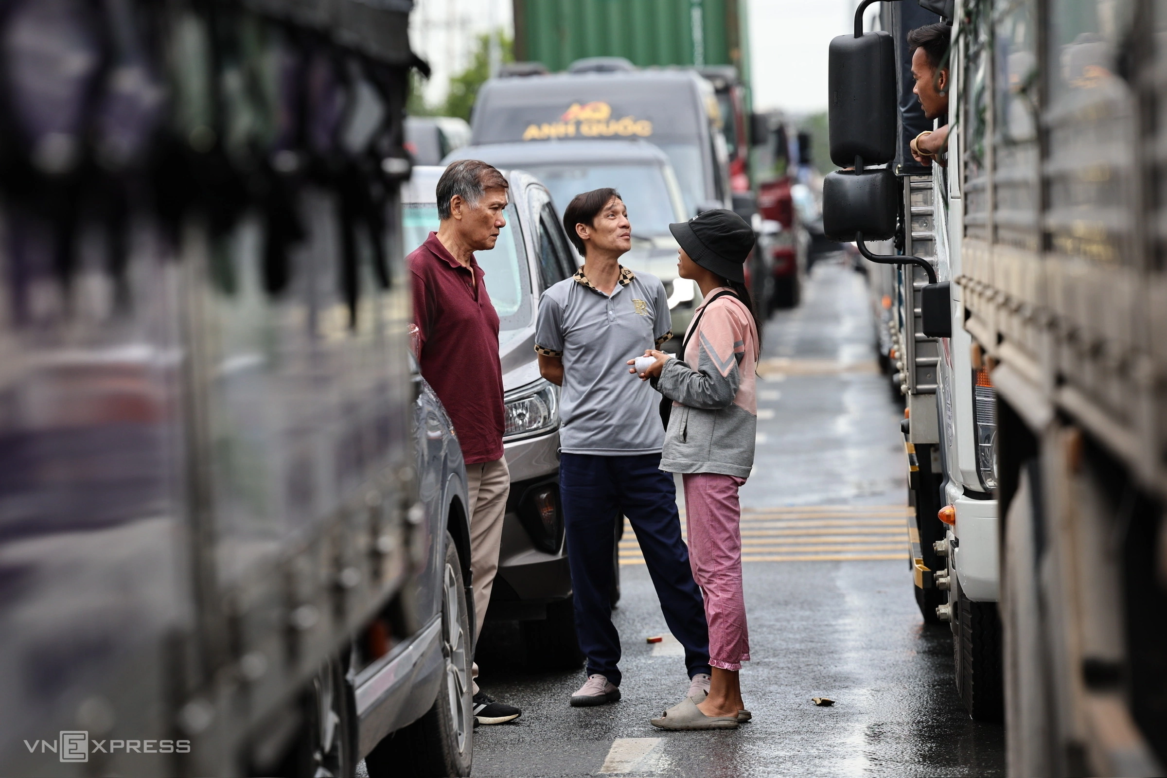 Nhiều tài xế, nhân viên xuống đường trò chuyện hoặc gọi điện cho người thân (ảnh sau) trên đường 319 qua xã Nhơn Trạch.