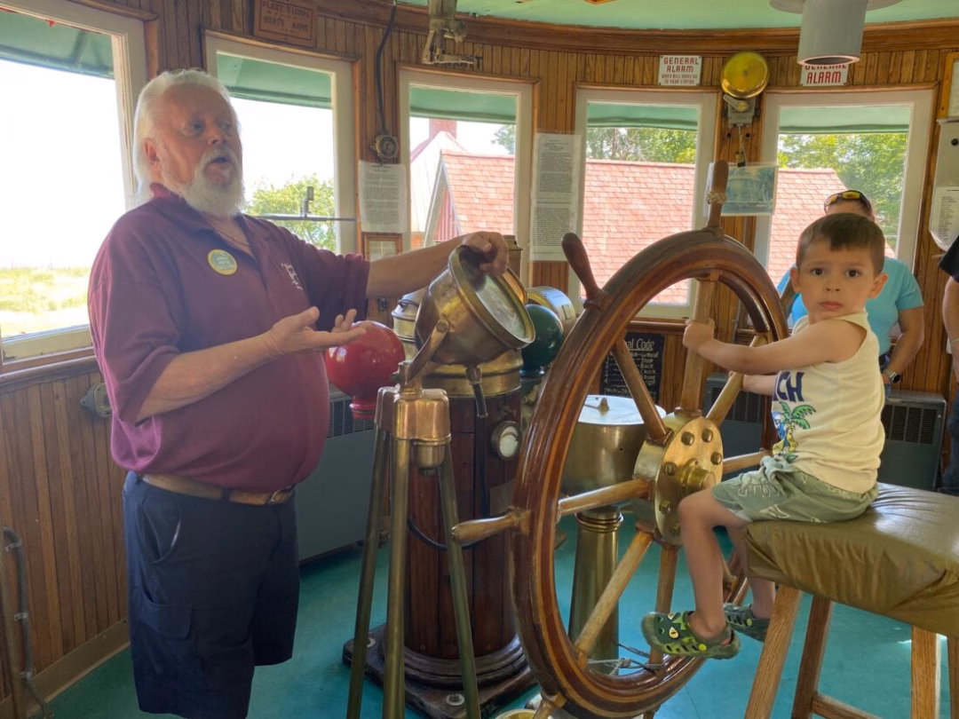 Điểm đến tuyệt vời: Tháp hải đăng Forty Mile Point trên bờ hồ Huron News Photo by Darby Hinkley “Muffin” is a very knowledgeable volunteer at Forty Mile Point Lighthouse. He is seen on July 8 giving a presentation inside the Calcite, a historic ship located on the lighthouse grounds. At the ship’s wheel is 4-year-old Dallas Foglesong, visiting with his family from San Antonio, Texas.