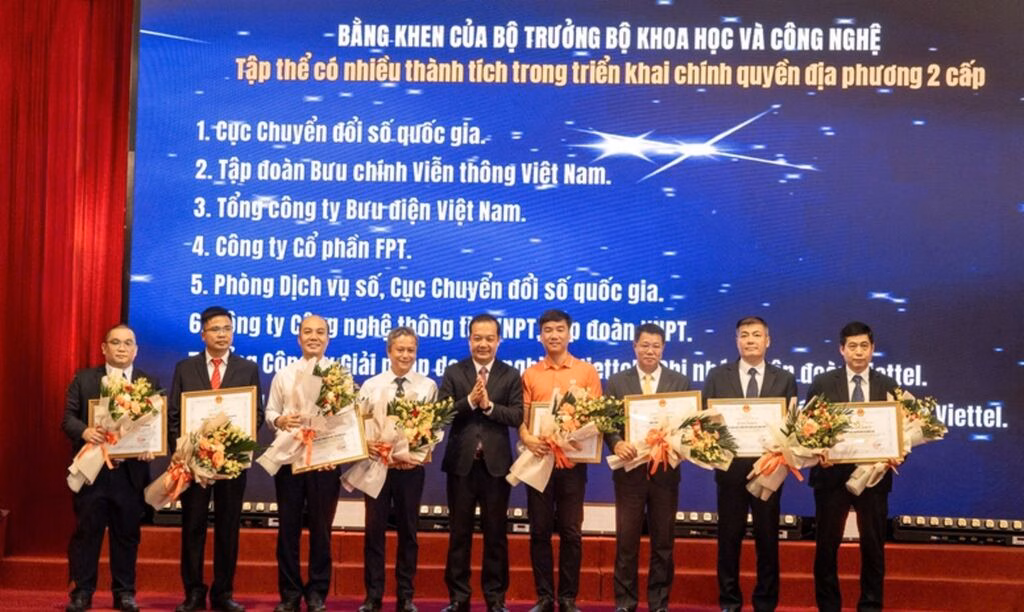 Đại diện FPT (áo cam) nhận bằng khen của Bộ trưởng Bộ Khoa học và Công nghệ cho những đóng góp trong việc chuyển đổi các hệ thống công nghệ thông tin quan trọng đáp ứng mô hình chính quyền 2 cấp