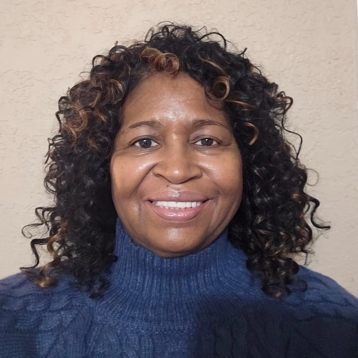 Smiling reviewer with curly hair wearing a textured turtleneck sweater