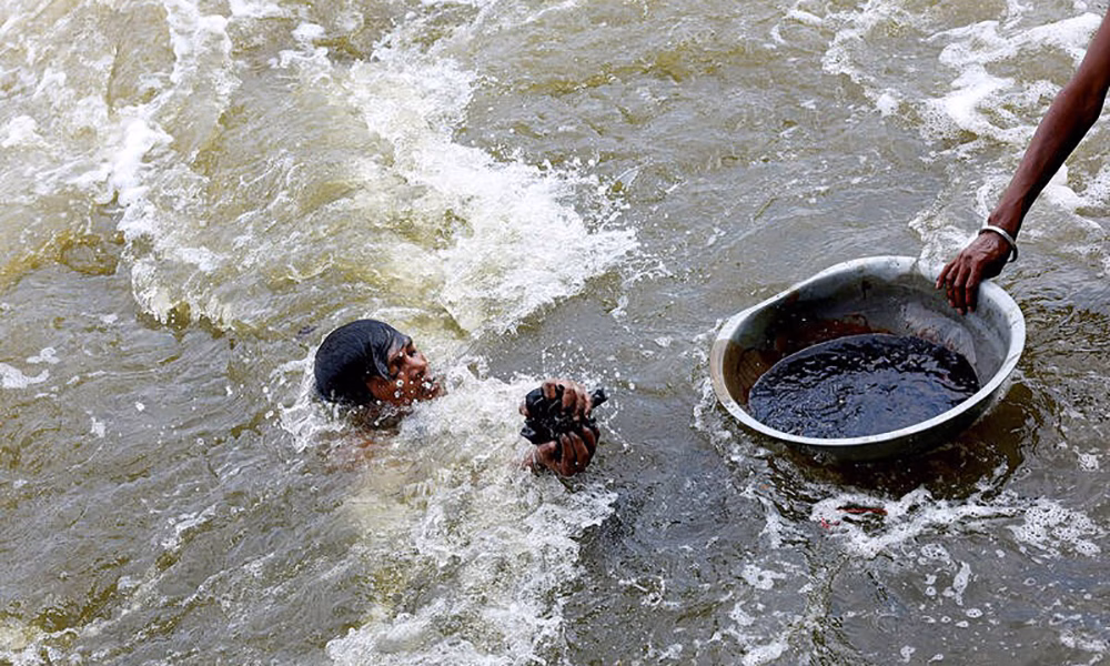 Một “gotakhor” đang ngụp lặn ở sông Yamuna để hy vọng tìm kiếm được vật phẩm có giá trị do các tín đồ Hindu thả xuống khi hành lễ