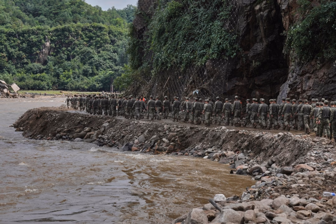 Mưa lũ càn quét Bắc Kinh, 30 người thiệt mạng Binh sĩ Trung Quốc hành quân dọc một tuyến đường bị nước lũ làm hỏng, trên đường giải cứu dân làng mắc kẹt trong vùng núi ở Mật Vân.
