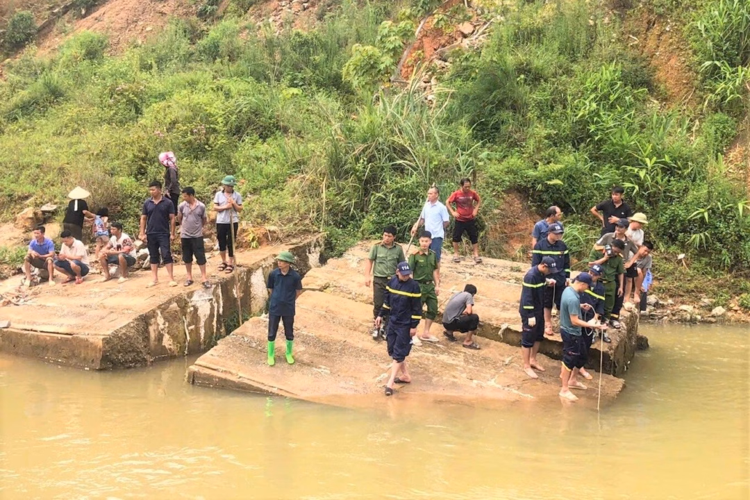 Người thân và người dân mong ngóng thông tin tìm kiếm chị Tin sau nhiều giờ bị nước lũ cuốn mất tích (Ảnh: Ngô Thủy).