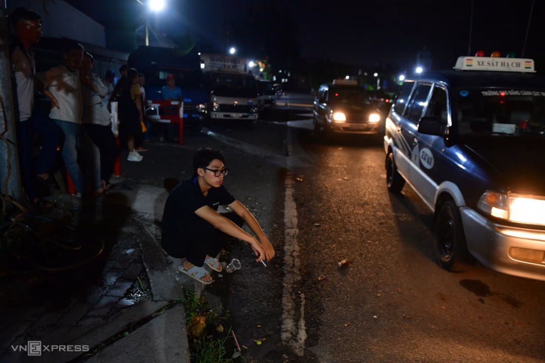 Cạnh đường chạy, nhiều người chăm chú quan sát các thí sinh thực hành bài chạy giữa trời tối. Anh Nguyễn Quang Vũ, 34 tuổi, cho biết đã có lịch từ 3/2025 nhưng sau đó bị hoãn, đến nay mới được thi.