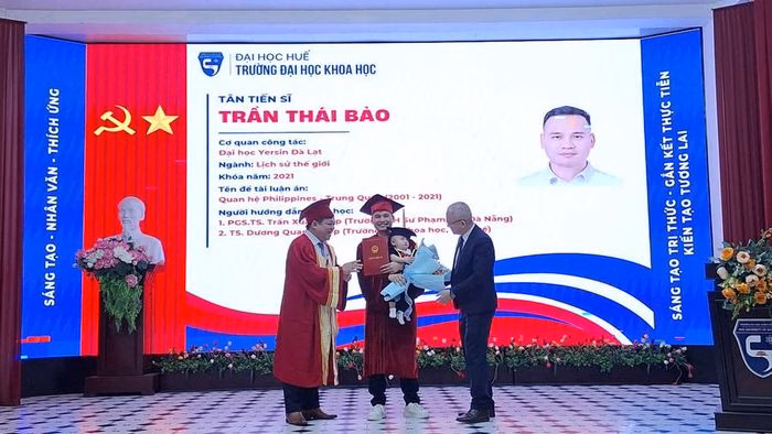 T&acirc;n tiến sĩ nhận bằng c&ugrave;ng con nhỏ tr&ecirc;n bục