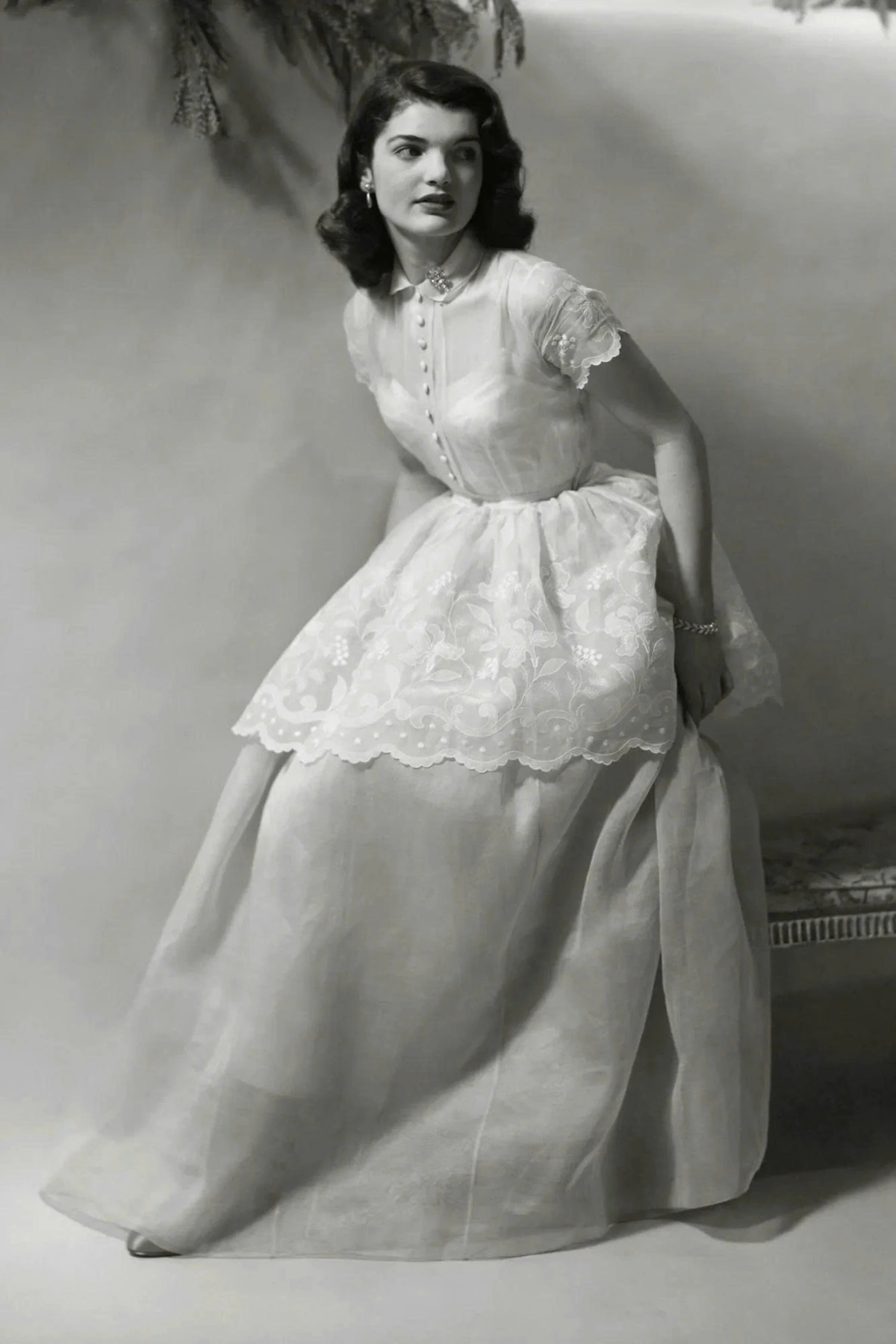 Phong cách vượt thời gian của Jackie Kennedy Trong bức ảnh chân dung khi mới 18 tuổi, bà Jackie diện chiếc váy trắng tay ngắn với phần yếm thêu ren, toát lên vẻ trong sáng và dịu dàng.