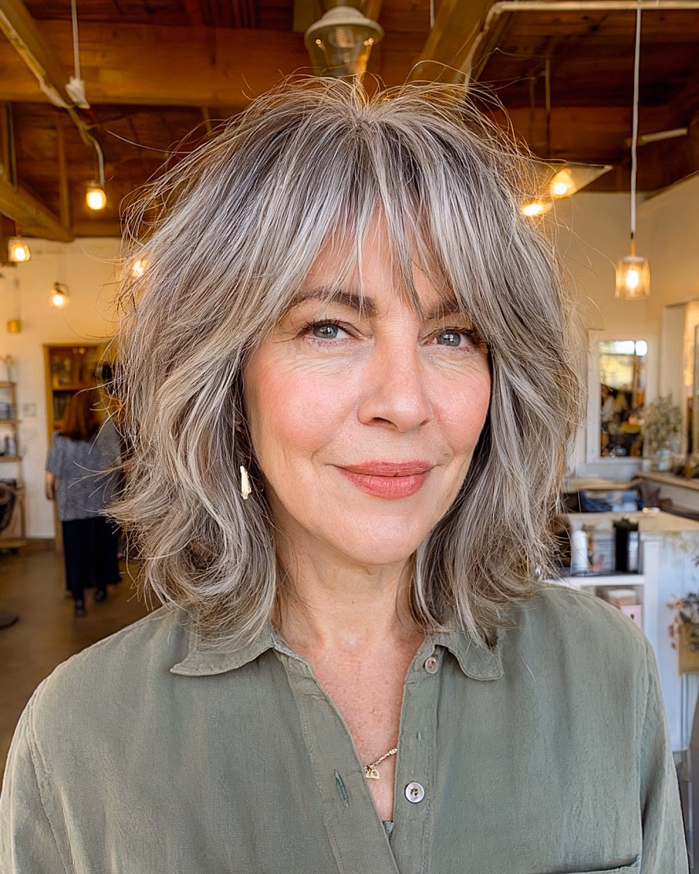 Shaggy shoulder-length haircut with textured layers and gray blending for women over 60
