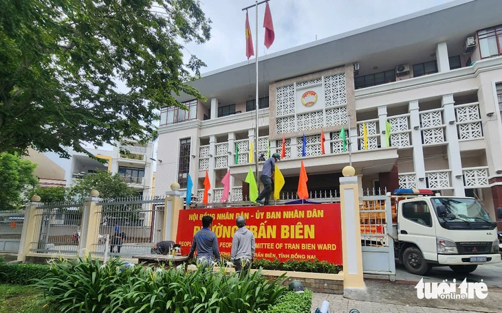 Công nhân trang trí cờ tại trụ sở Hội đồng nhân dân, UBND phường Trấn Biên