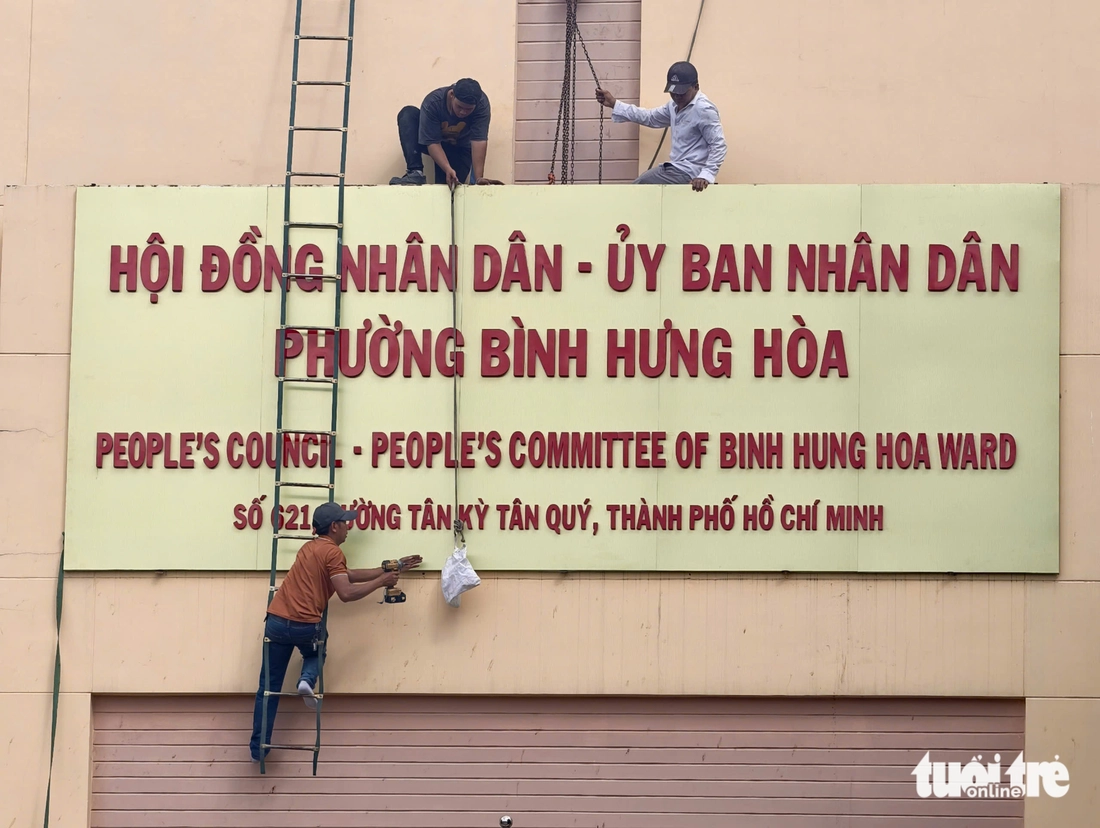 Một số người thuộc đơn vị thi công lắp đặt bảng tên trụ sở Hội đồng nhân dân - Ủy ban nhân dân phường Bình Hưng Hòa