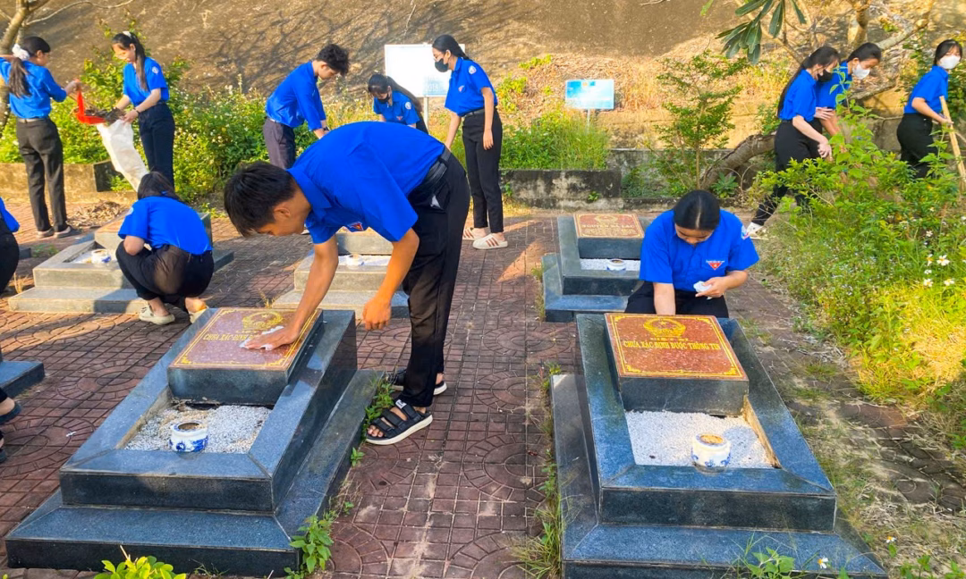 Thanh ni&ecirc;n v&agrave; c&ocirc;ng an dọn dẹp nghĩa trang liệt sĩ