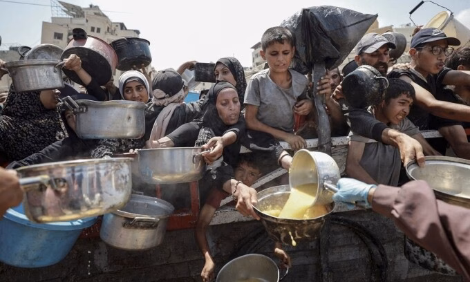 Người dân trèo lên các xe tải chở hàng viện trợ vào Gaza hôm 29/7. Ảnh: Reuters