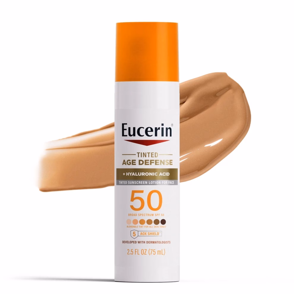 3 sản phẩm chăm sóc da đáng tiền cho chị em Eucerin Tinted Age Defense sunscreen with hyaluronic acid SPF 50, displayed with a swatch of its color in the background
