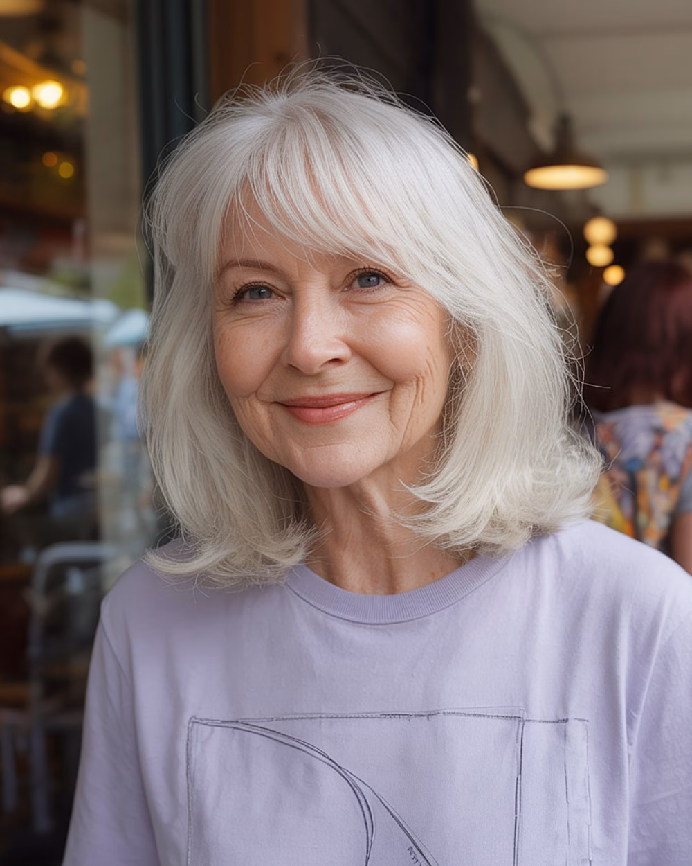 White shoulder-length hair with wispy curtain bangs and soft layers flattering a round face shape