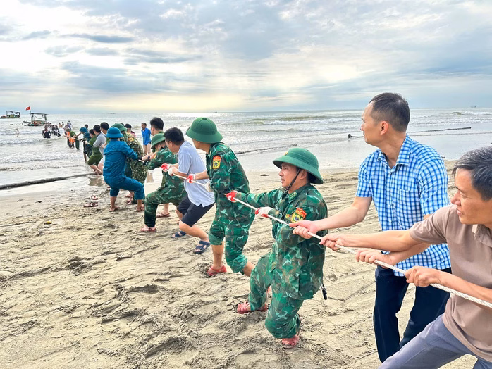 Đồn Biên phòng Hà Tĩnh cứu hộ thành công 33 người trong cơn mưa lớn và sóng biển dữ dội Lực lượng chức năng cùng người dân kéo một chiếc thuyền của ngư dân bị gió lớn đánh lật úp trên biển