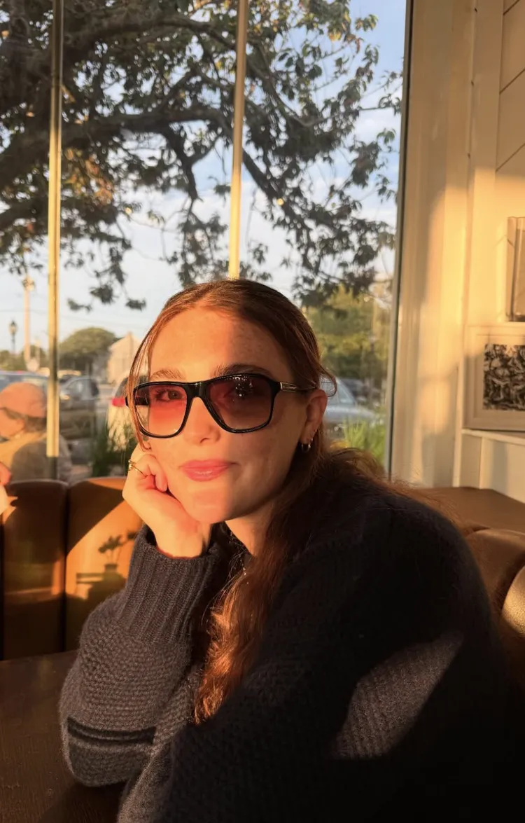 Julianne Moore's daughter Liv in sunglasses in a sunlit room with her head in her hand