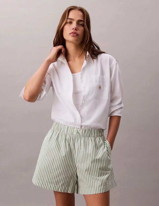 Chiếc quần boxer shorts với chất liệu cotton mỏng nhẹ, họa tiết sọc xanh pastel xen trắng mang lại cảm giác mát mẻ và năng động. Fashionista Faye phối cùng sơ mi trắng oversized xắn tay, bên trong là tank top giúp cân bằng giữa vẻ thoải mái và thanh lịch