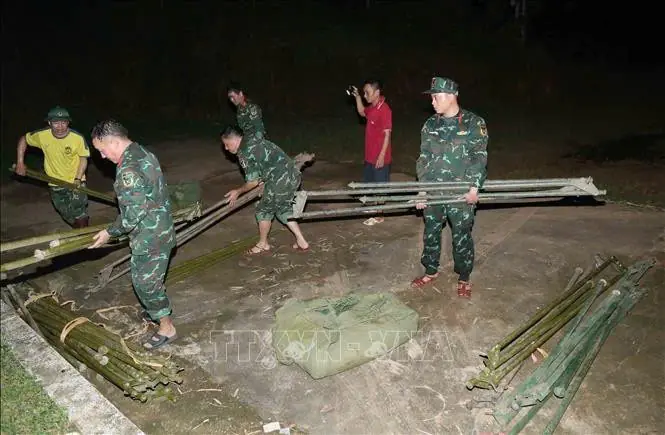 Cán bộ, chiến sĩ Ban chỉ huy phòng thủ khu vực 2 - Sông Mã thức đêm xuyên 27/7 để dựng nhà bạt cho các hộ phải di dời khẩn cấp để tránh trú thiên tai, lũ ống, lũ quét. Ảnh: Quang Quyết - TTXVN.