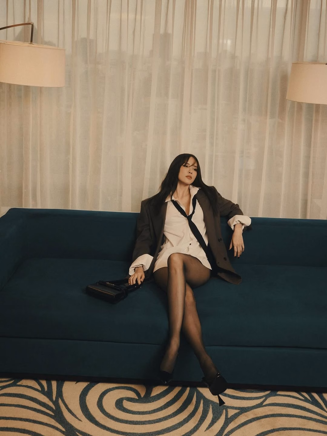 Trong bộ ảnh, Thiều Bảo Trâm diện một chiếc áo sơ mi trắng dáng rộng kết hợp cùng blazer màu nâu đất phóng khoáng và cà vạt buông lơi, tạo nên vẻ ngoài vừa lịch lãm, vừa phá cách.