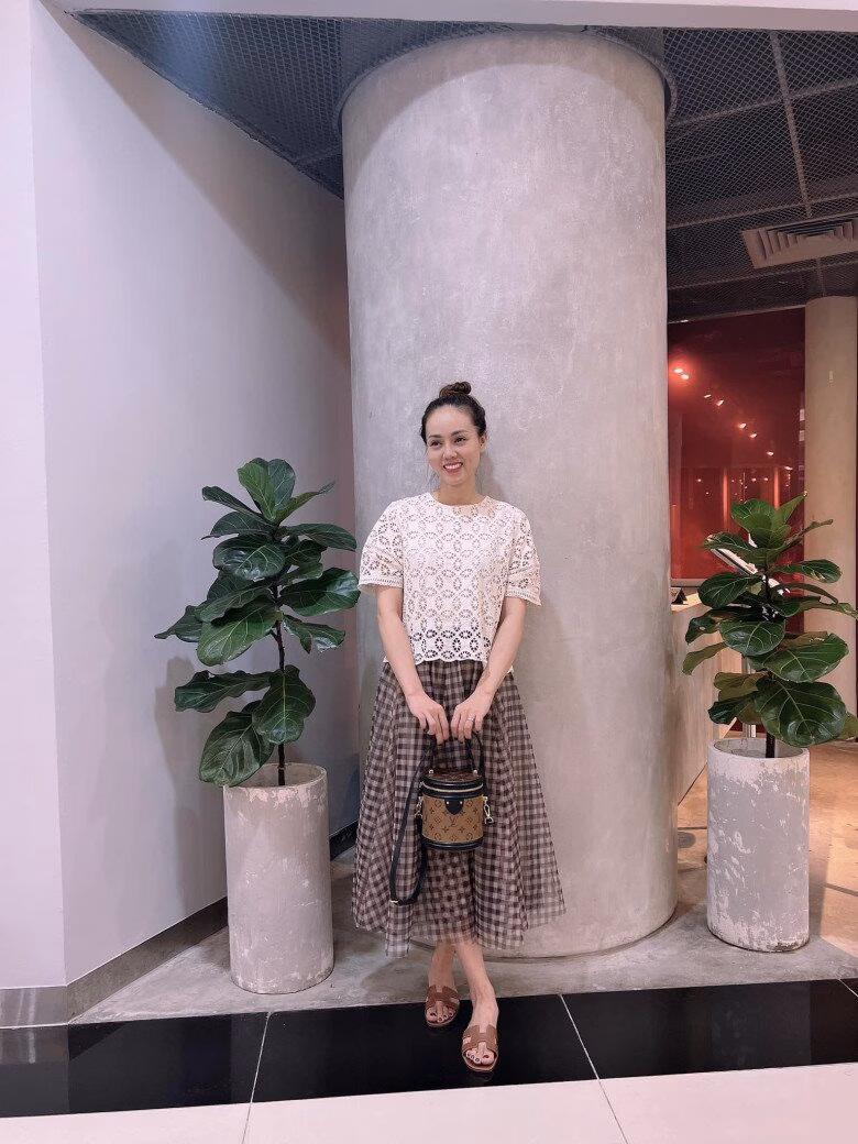 Nhan sắc và phong cách thời trang đỉnh cao của 2 bà xã Công Lý Bà xã Công Lý phối chiếc váy xoè với hoạ tiết caro cùng áo trắng hoạ tiết, xách thêm túi LV dạng lồng cơm xa xỉ.