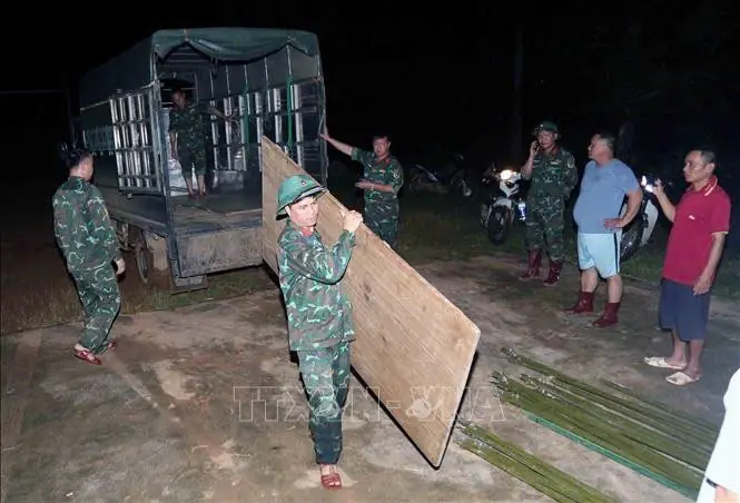 Cán bộ, chiến sĩ Ban chỉ huy phòng thủ khu vực 2 - Sông Mã thức đêm xuyên 27/7 để dựng nhà bạt cho các hộ phải di dời khẩn cấp để tránh trú thiên tai, lũ ống, lũ quét. Ảnh: Quang Quyết - TTXVN.