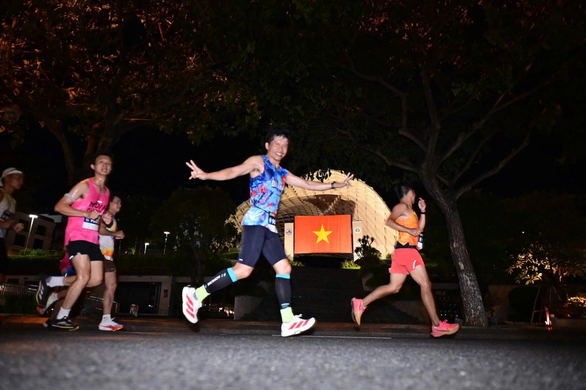 VĐV Huỳnh Anh Khôi vô địch VnExpress Marathon Đà Nẵng cự ly 42km VĐV tạo dáng với lá cờ tổ quốc phía trước cung thể thao Tiên Sơn.