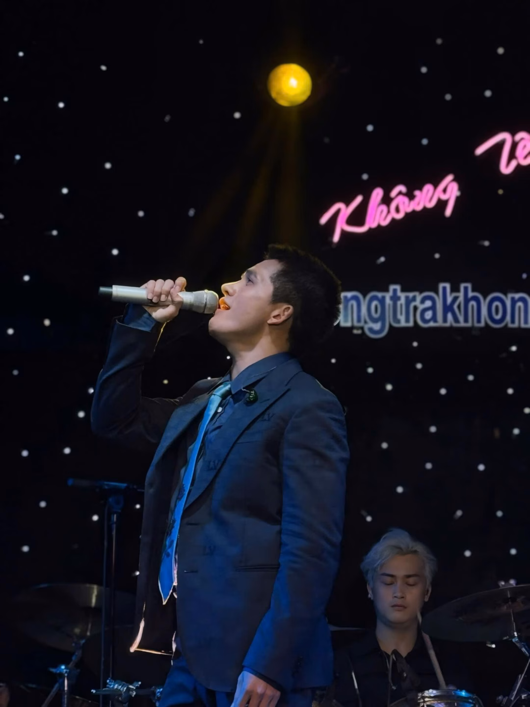 May be an image of 2 people, microphone, dinner jacket, concert and text that says 'La Không ngtrakhon'