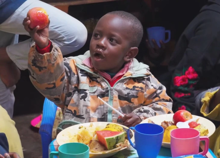 Khuôn mặt hớn hở của một bé Kenya khi cầm trái táo Khuôn mặt hớn hở của một bé Kenya khi cầm trái táo