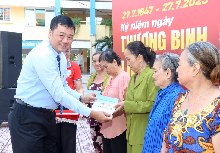 Bí thư Đảng ủy phường Phú Định Phạm Ngọc Muôn trao tặng thẻ bảo hiểm y tế cho người cao tuổi có hoàn cảnh khó khăn - Ảnh: THẢO LÊ