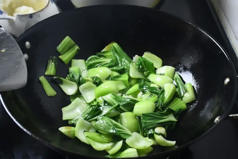 Cải ch&iacute;p đang được x&agrave;o, l&aacute; chuyển m&agrave;u xanh đậm