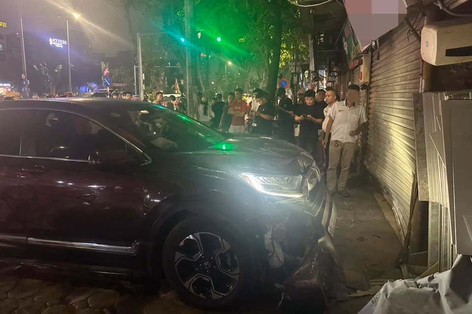 Chi tiết hư hỏng đầu xe và cửa cuốn tiệm cầm đồ Phần đầu ô tô bị hư hỏng nặng sau khi lao vào cửa cuốn tiệm cầm đồ